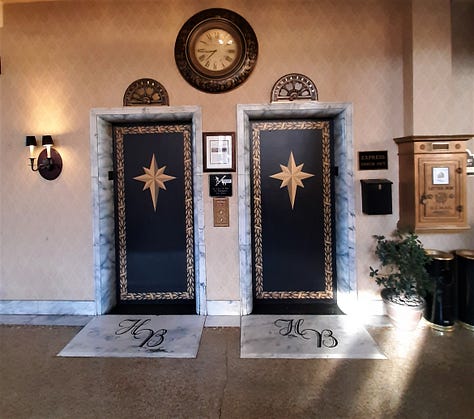 A collage of photos showing the Historic Hotel Bethlehem, including two photos of the 9-story brick exterior, and interior pictures of the elevators, white marble staircase with polished handrail, open doors to the ballroom with a glistening chandelier, and two photos of the lobby, with luxurious black leather furniture in front of a huge arched window with a Christmas wreath in the middle. Also a look inside a room of a bed with a robe lying on the end.