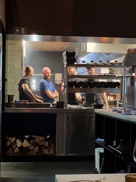 Photo 1: view from our table at Maven showing the sides of beef hanging to dry age and the meat select counter at ground level. Photo 2: photo of Dave in the kitchen talking to 3 Maven chefs. Photo 3: photo of main course including Angus steak, Wagyu steak, frites, and caesar salad.