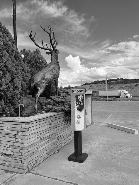 Gas station with clouds in the sky, the flat desert, and an old-school phone booth 