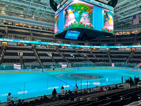 images of hockey arena, 2 girls wearing masks, a mascot shark on ice