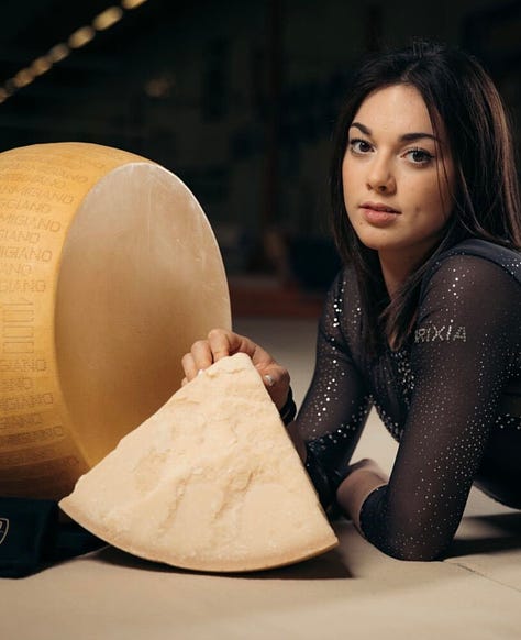 Giorgia Villa in a gymnastics leotard hugging a wheel of parmigiano reggiano, doing a handstand