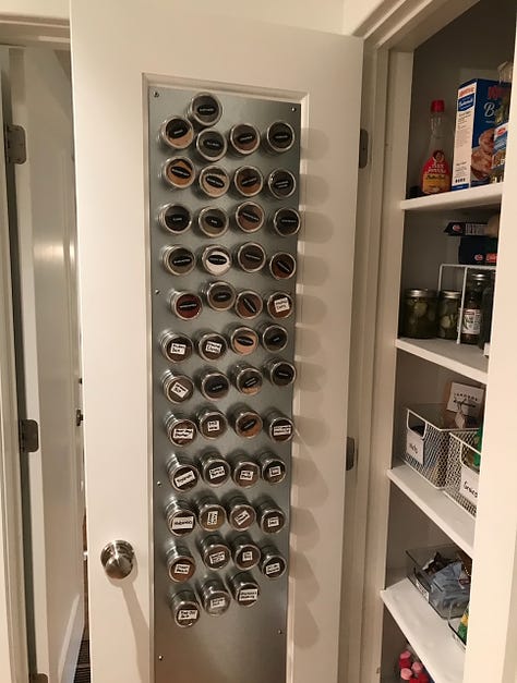 Large pantry with magnet spice wrack on the open door and storage containers on the shelves.