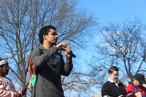 Left image: one small square pink poster reading "I support unions" and a person in a red cap holds up a poster in rainbow lettering "this is what DEMOCRACY looks like." Middle image: A young Brown man stands to the left of the image facing right holding a microphone and cellphone, a white person with short brown hair and a black shirt stands looking downward in the right corner. Right image: a white poster with black text that reads "The working class holds the power" and a red flag with the letters FRSO (Freedom Road Social Organization) flies in the background