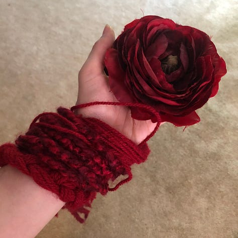 Costume trials in black pants and crop top, with cream and gold belt and bra covered in red tassels and roses. The last photo is one of the roses held in the palm with the red yarn dangles twined around the wrist.