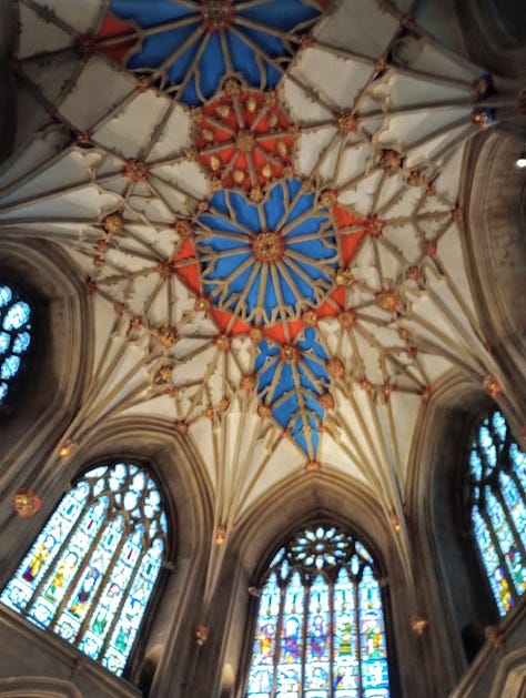 Exterior side of stone building with clock tower, interior with large stained glass window, interior with smaller stanined glass windows, altar, and ceiling decoration that looks like large star, large star, gift shop fll of merch in side chapel, cake slice and cup of tea