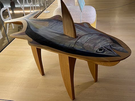 Two images of a wooden table carved into the shaped of a tuna fish with a painted tuna fish painted on top