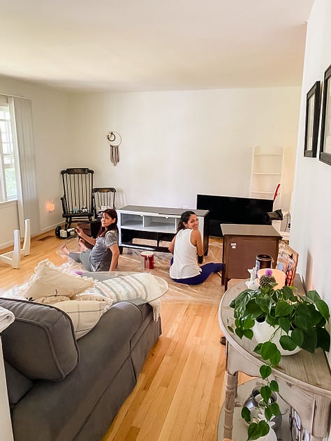 Photo of a paved walking trail surrounded by lush vegetation and a deer on one side, a round embroidery hoop with an image of a pineapple, a woman smiling and presenting the piles of fresh pasta she made from scratch, a selfie photo of woman and her dad painting a piece of furniture, a photo of a woman and her mom sitting on the floor painting a piece of furniture, a selfie photo of a woman and her parents sitting down at the dinner table to eat barbecue food, a photo of a woman and her dog looking out the window, a photo of a LOVE sign in a grassy, woody green forest, a selfie photo of a woman with her parents and dog behind her walking in the opposite direction.