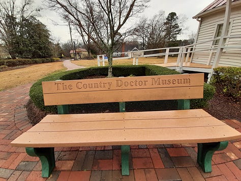 Exterior photos of the Country Doctor Museum, showing a yellow building with red room, a bench outside with the words Country Doctor Museum, and an original country doctor building.