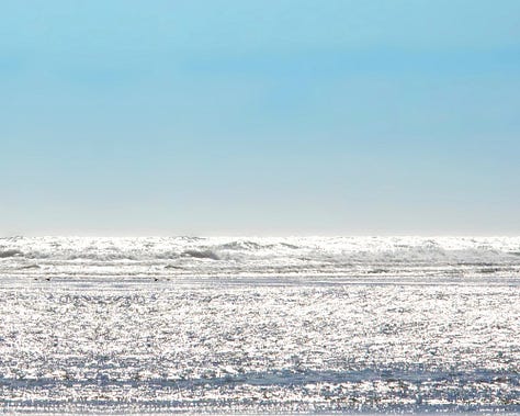 A selection of three images shows: a horizon of blue sky and sparkling ocean; a close-up of glistening sandy beach; a green heart-shaped sea glass.