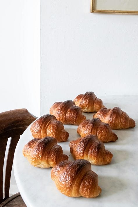 A gallery of photos, a loaf of rustic bread, a table with croissants, two seeded buns, a bowl of chocolate mousse, a scoop of vanilla and chocolate ice cream in a stemmed glass and a crunchy waffle topped with slices of fruit.