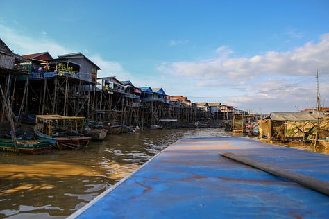 Various images from a day of photograph at Tongle Sap, including a man in a motorcycle helmet pointing, a boat in a river beside stilt houses, some kind of racoon animal in a cage, local children torturing shrimp, a man sitting on a railing, a young girl looking bored while trying to sell beer, and two men standing on a wall over a huge crocodile.