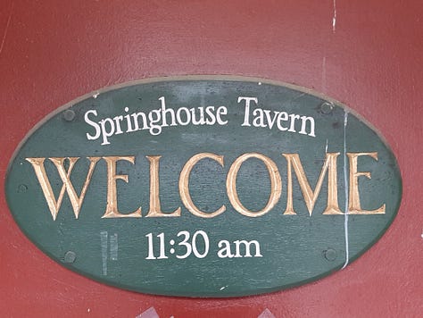 Outside of the stone Dobbin House restaurant; a welcome sign for the Springhouse Tavern and a closeup of candle-style lighting/ A sign for the Slave Hideout Museum, and a display of 3 slaves hiding in a crawl space. The owner of the restaurant stands in front of a huge stone fireplace in a room set up as a colonial kitchen.