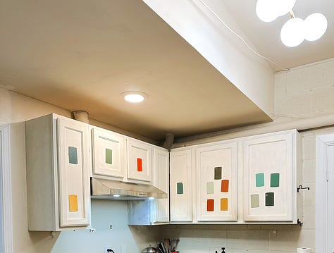 a man installs new lighting. Paint chips decorate the cabinets.
