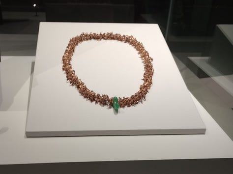 From left: Necklace made of gold nuggets and jade ornament, gold and genstone-encrusted dagger sheath, and a small cobalt blue drinking glass