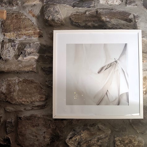 Three pictures: the first, a desk in front of a window. There is a mug and writing implements on it. The middle picture has a coffee cup and coffee. The final picture shows a print of Alison Watt's Sabine on a brick wall