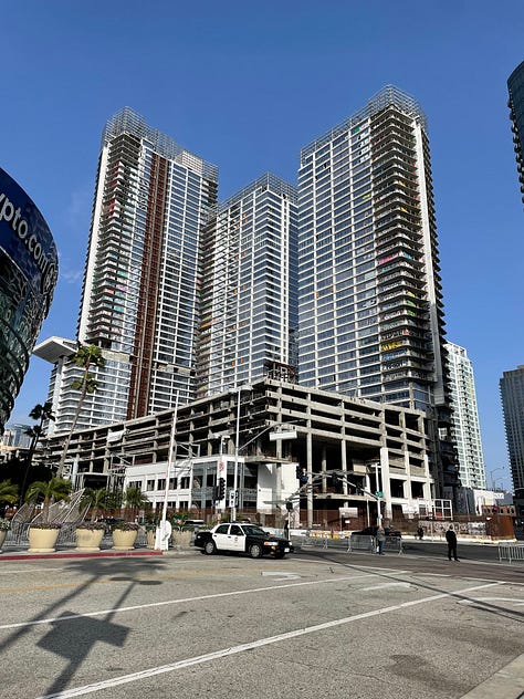 An unfinished building with graffiti running up its seen from a distance and up close balconies against a blue sky