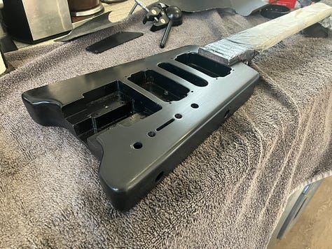 An image gallery showing a headless guitar being stripped down, sanded, repainted, and reassembled. By the end, it's blue with black and white stripes, and looks extremely shiny.