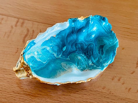 Three images of hand-painted oysters. They have paint on them in a gorgeous blend of cerulean, turquoise, gold, and white., resembling the ocean.