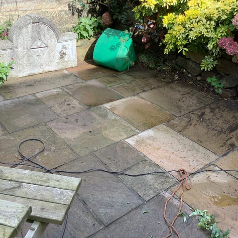 Five pictures of the patio in various stages of repair. First being pressure washed, second, three men is hi-vis clothing are gathered round one flag ‘discussing’ the work needed, third is a pic of lots of lifted flags and a lot of mess, fourth is he revealed steps of York stone and the relaid and regrouted old flags of many colours, the first is a picture of fags that have been regrouted, the grout is ina contrasting colour. 