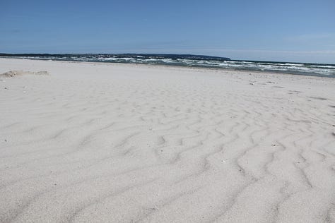 Fila di caseggiati, foto di un progetto, spiaggia vuota con mare blu.