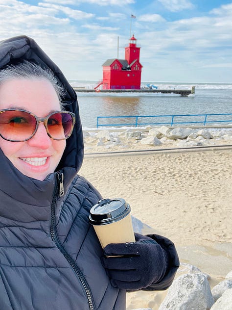 9 images in a gallery: an infrared sauna lit pink, luminaries on a snowy street at dusk, a candle and legs crossed on a yoga mat, a 3 year old boy in a blue coat plays in the snow, a 40 year old windswept woman walks by lake michigan and a red lighthouse, seasonal hand cream and chapstick, a seasonal soup in a red enamel pot, hot chocolate with marshmallows, and a cozy massage table