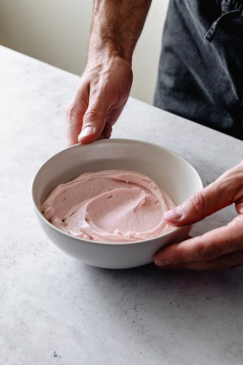 Three bowls of vegan American buttercream in vanilla, chocolate, and strawberry