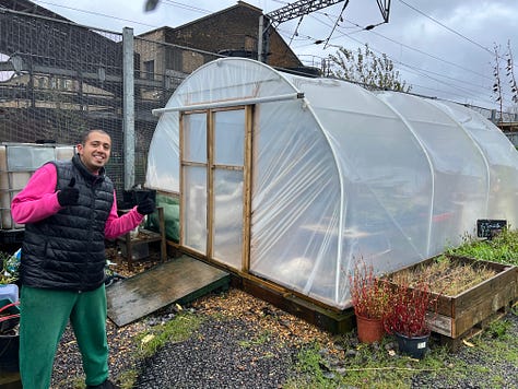 The Mobile Garden in Hackney Bridge, with planters and various crops, a polytunnel and signage saying "ALL WELCOME"