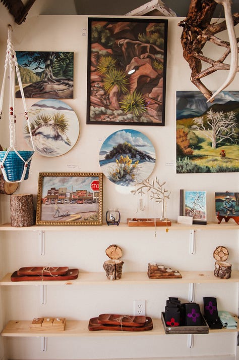 artwork depicting southwest plants and imagery hung salon style on white walls in a gallery.