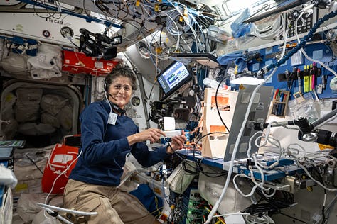 Two photos with Suni Williams, one with Butch Wilmore, both working with a weird desktop contraption that's a board with tubing and sponges attached to it, with a syringe at the top. It's all red/orange, which is the colour of the liquid used during the tests.