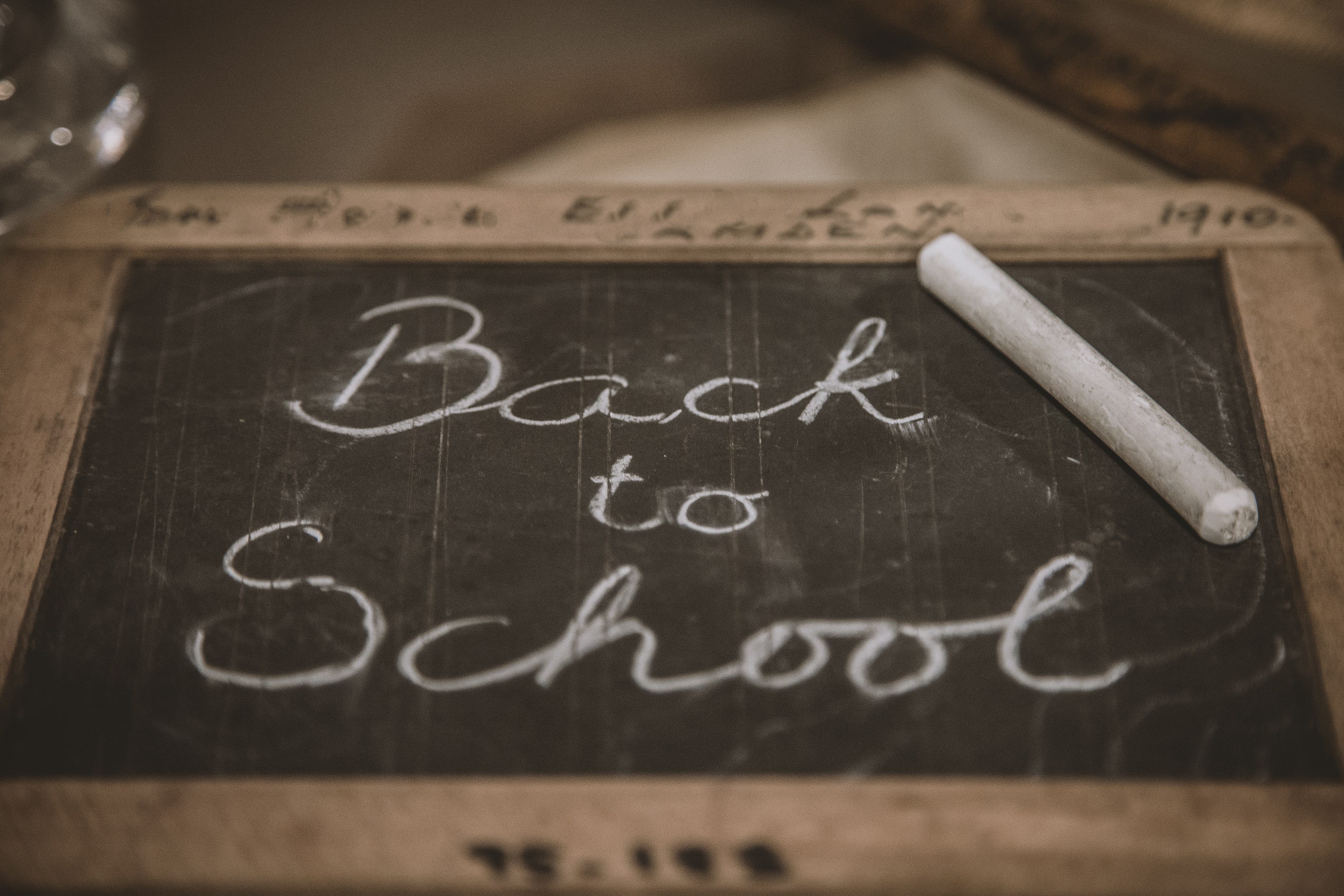 The words "back to school" written on a blackboard with a piece of chalk sitting on the side
