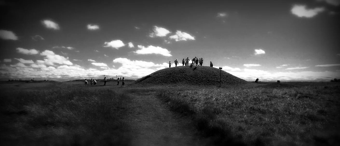 Black and white image of the Mound of Hostages with a crowd of people standing on top of it