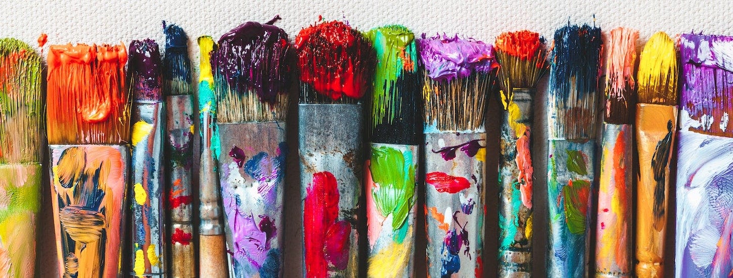 [Photograph: used paintbrushes of various colors and sizes]