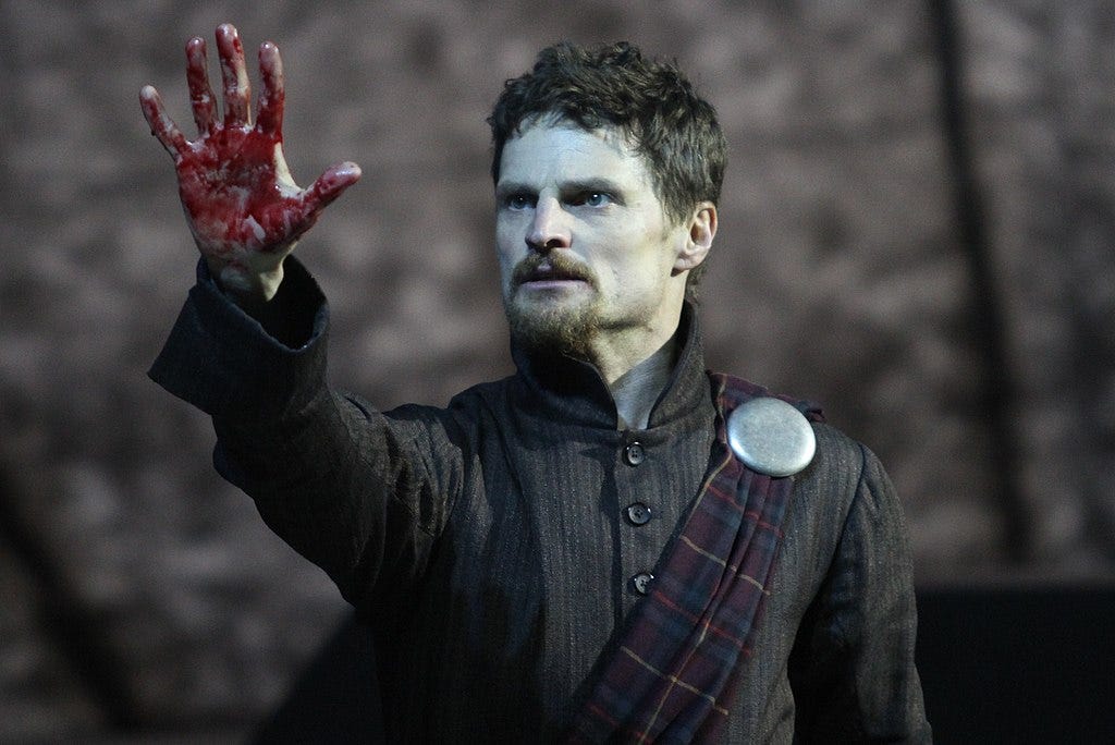 An actor playing Macbeth shows a bloody hand -- highlighting the play's murderous nature and relevance today