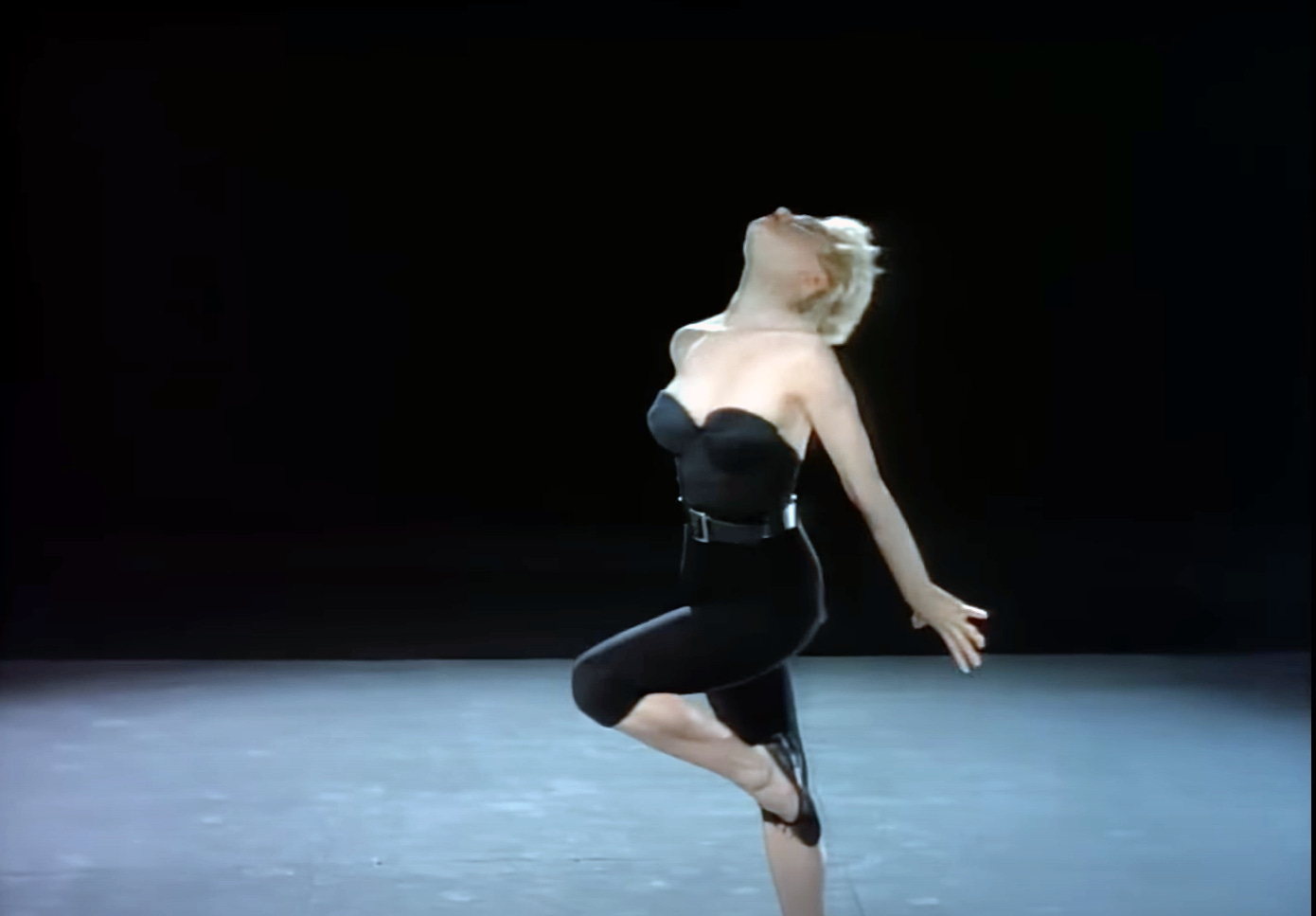 Madonna in the Papa Don't Preach video, dressed in black bustier and capri pants, dancing