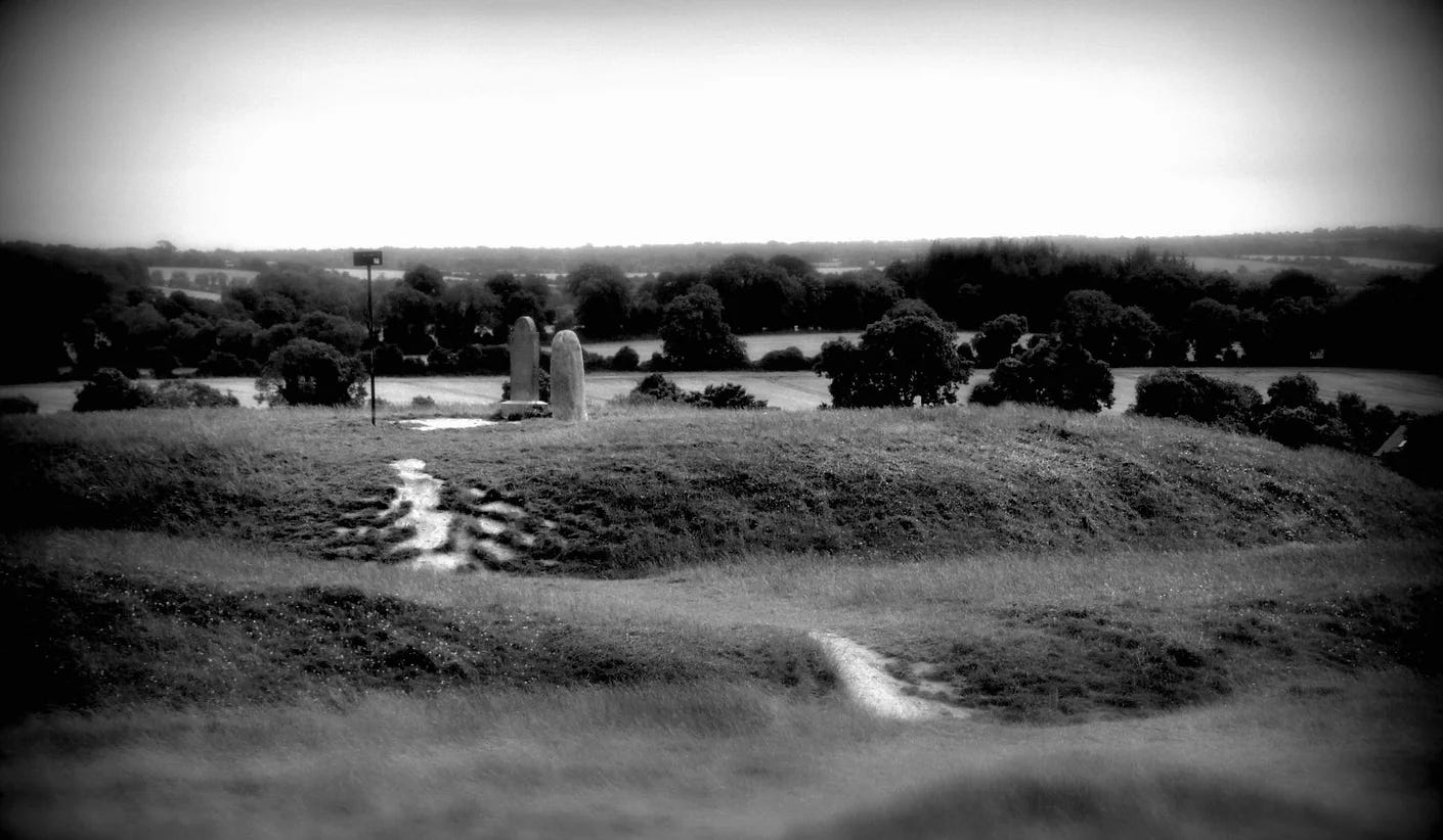 Black and white image of the Hill of Tara showing the  small standing stone known as the Lia Fail  set against the surrounding fields and woodlands of the local landscape