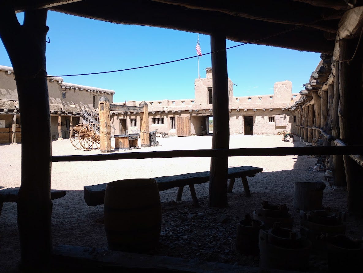 Low adobe building around a courtyard with walkway on roof, ecept for one side with two storeys. Dry and dusty.