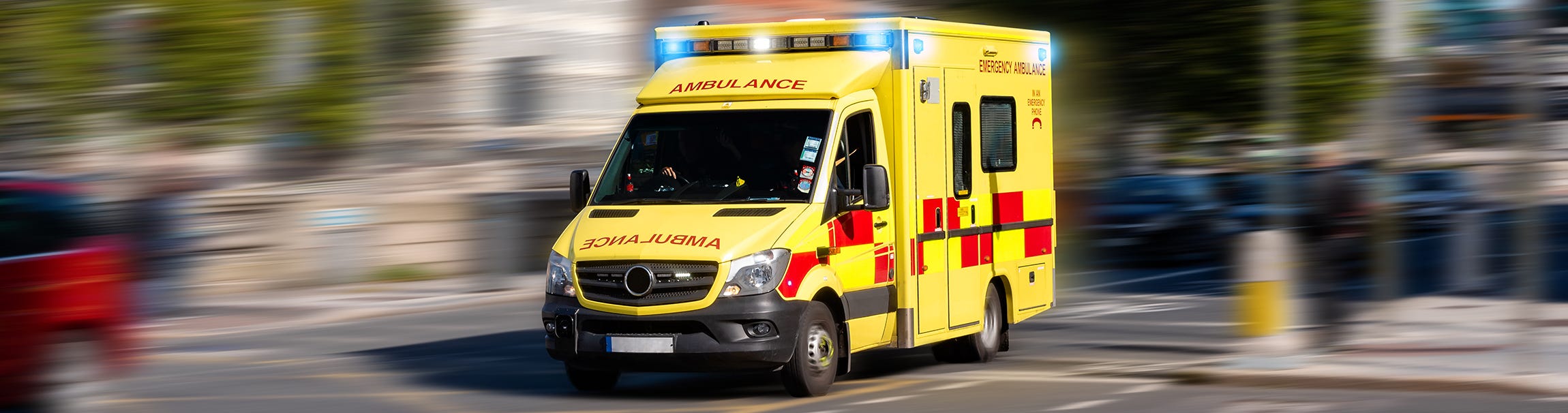 Image of an ambulance speeding through a blurred street scape