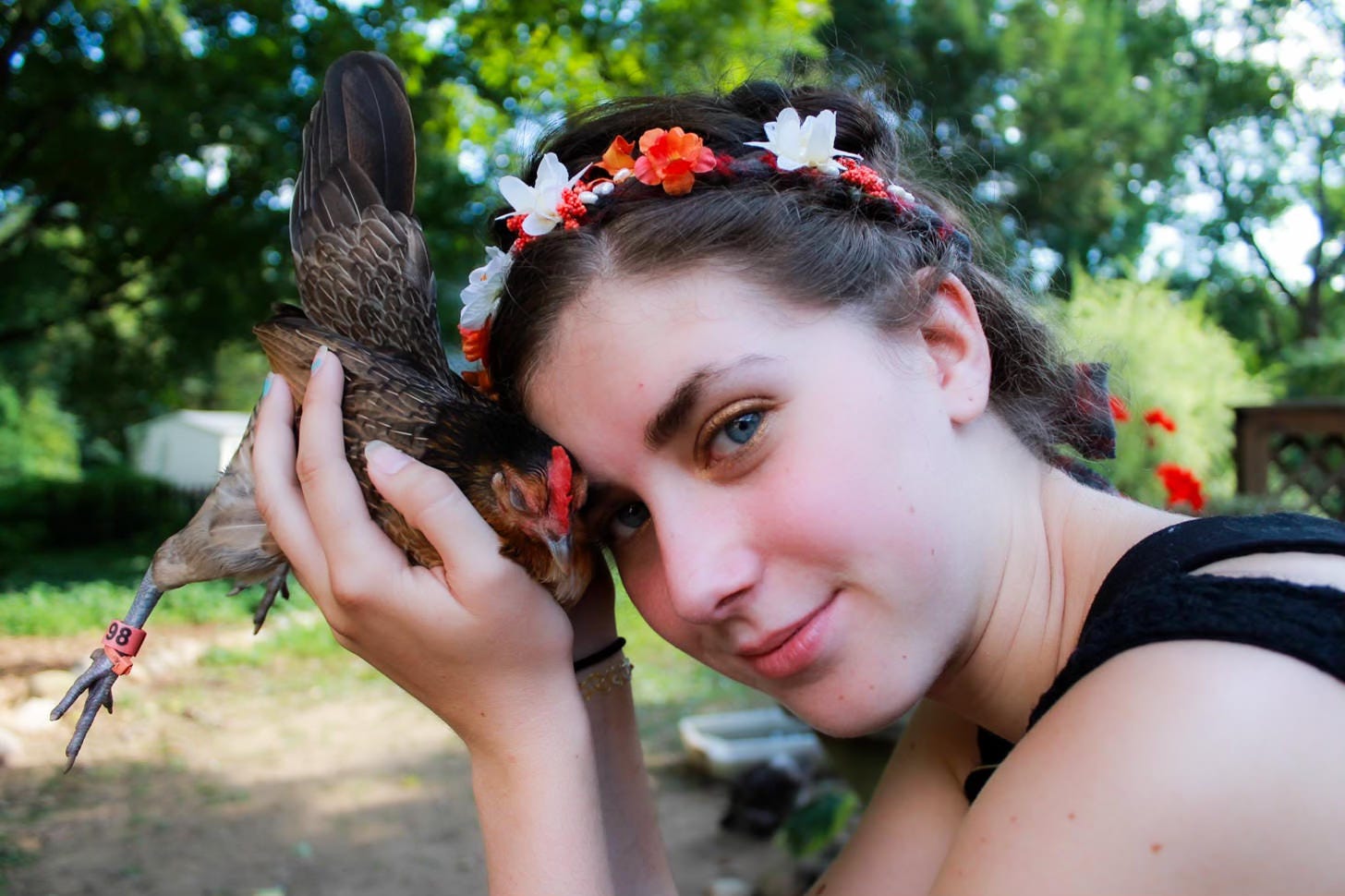 young woman holding small chicken next to her face