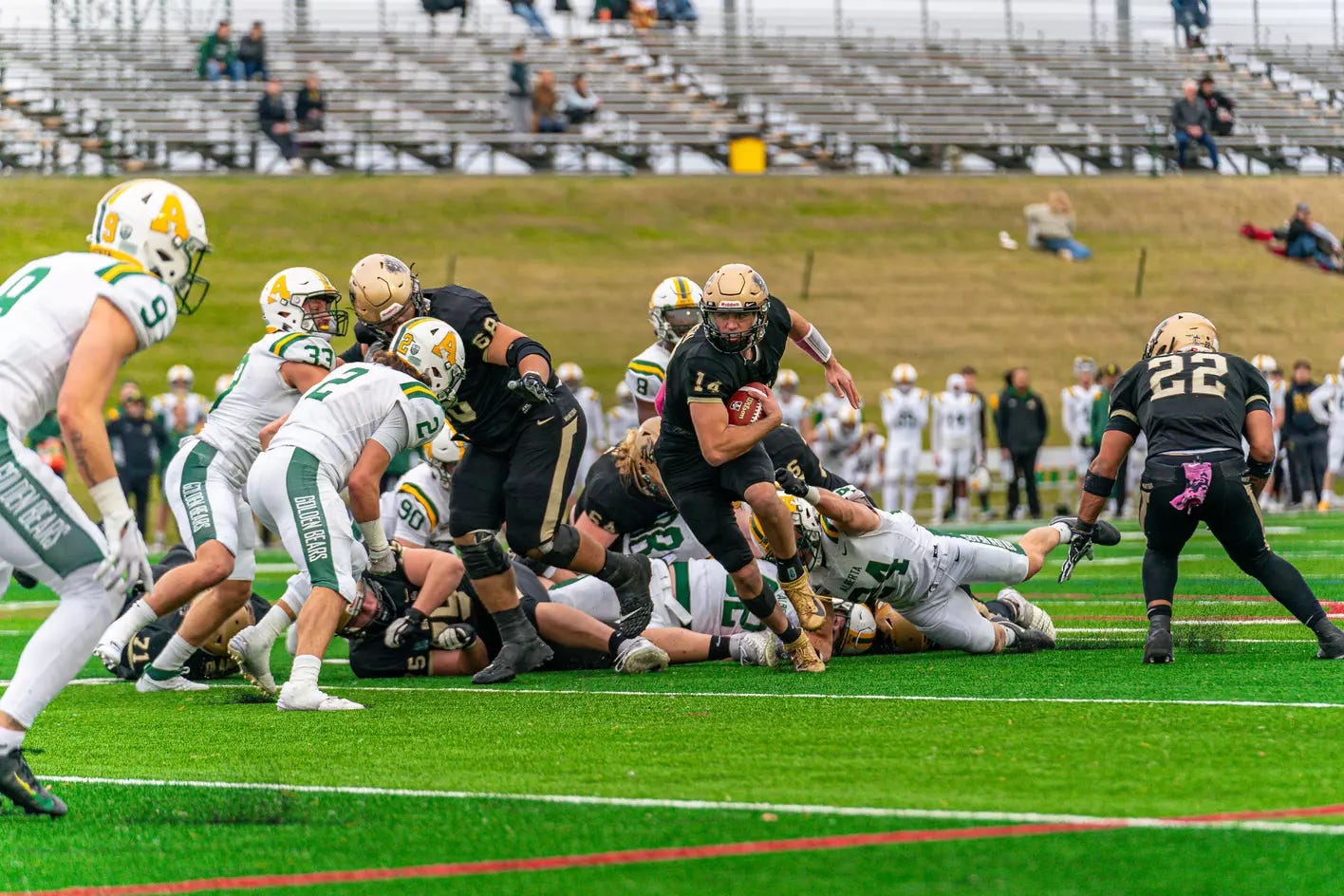 A football player runs with the football toward a group of defenders.