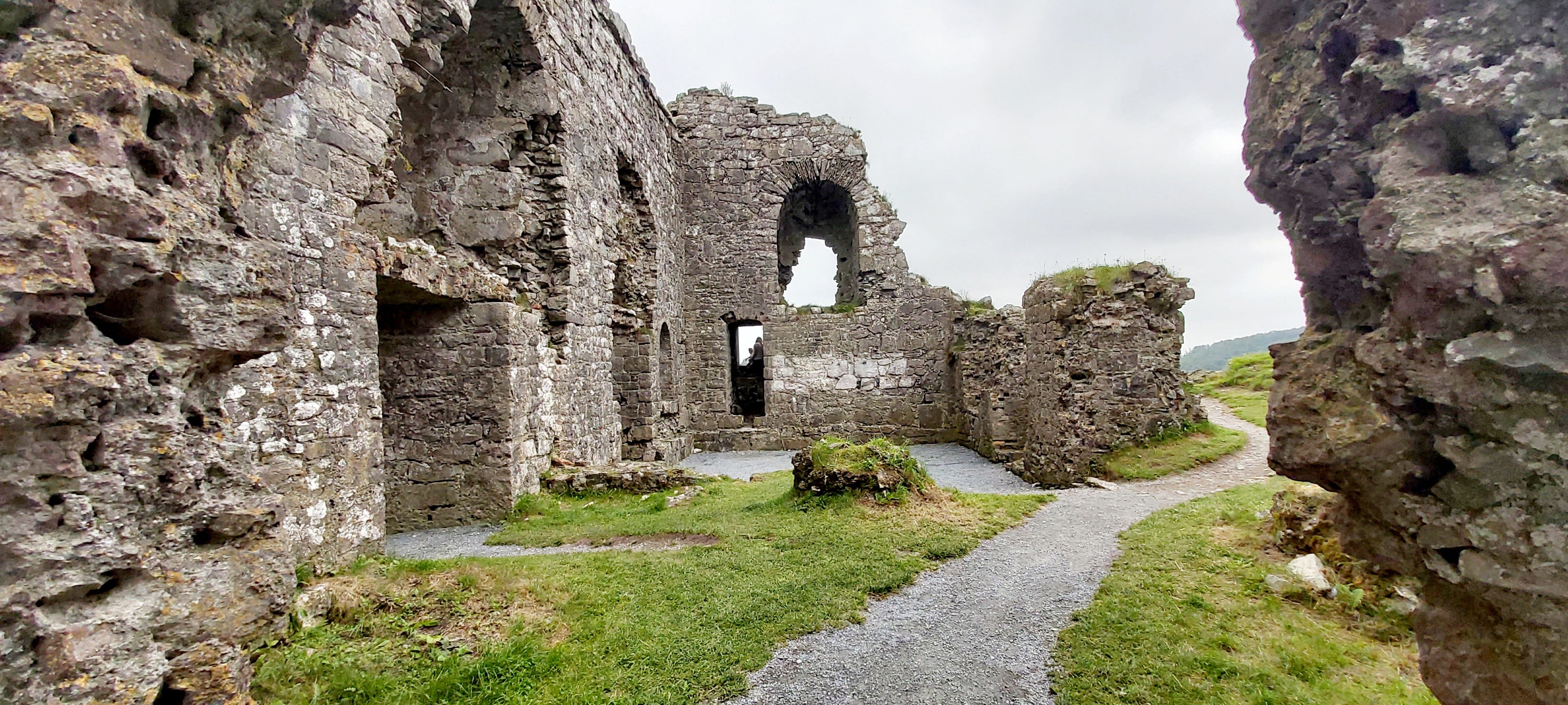 The ruined stone living quarters of Dunamase Castle, showing empty arched windows, narrow doorways, and alcoves which may once have served as fireplaces.