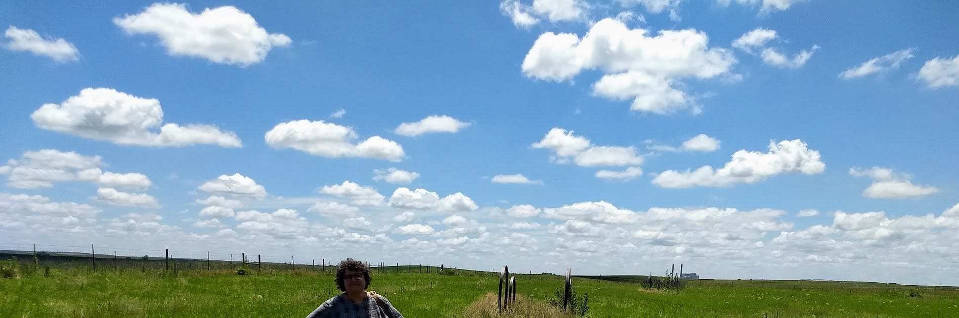 Annette in front of ghostly wagon wheels set on flat meadow valley with blue skies and puffy clouds Annette in front of ghostly wagon wheels set on flat meadow valley with blue skies and puffy clouds