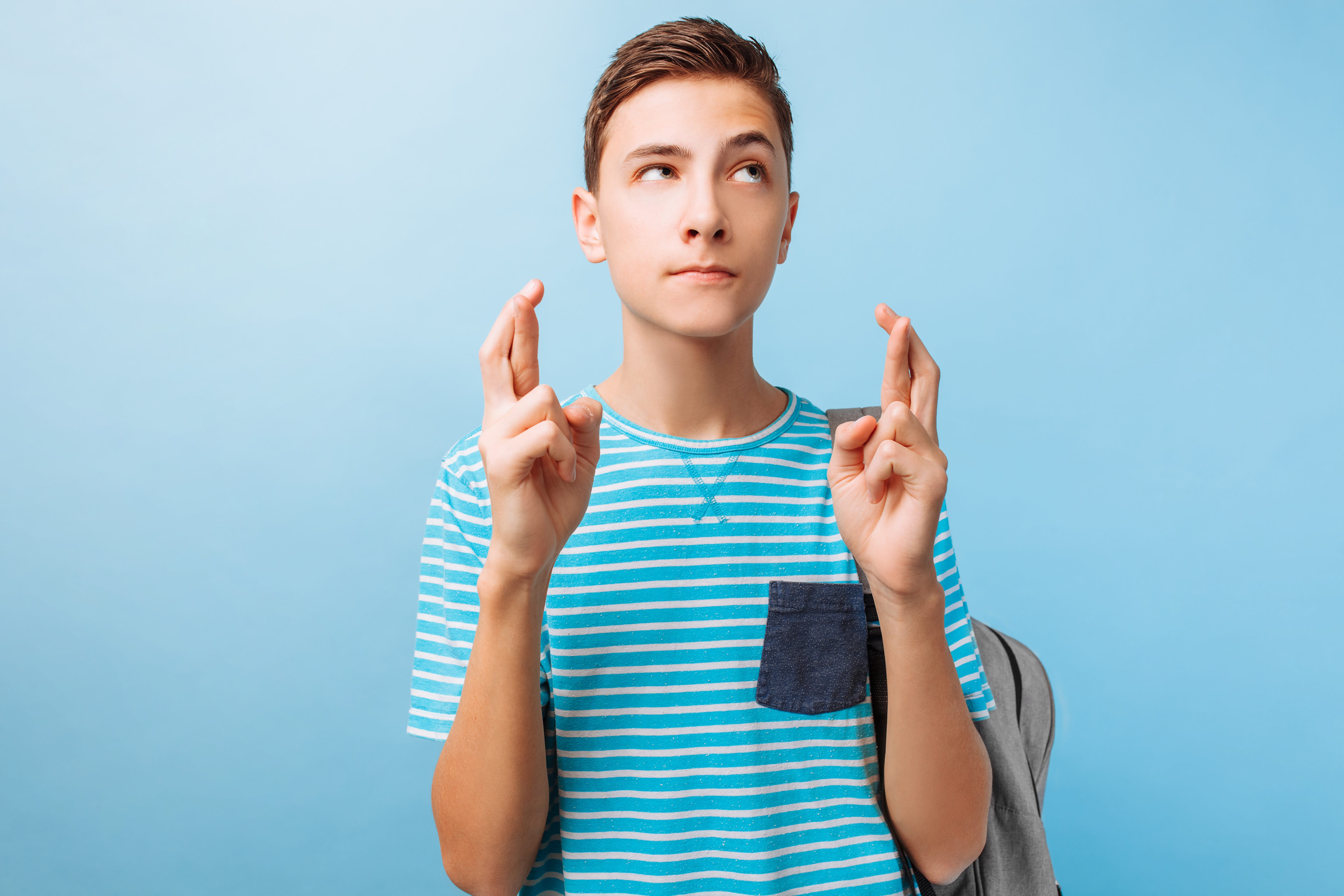 Teenage boy hoping, with fingers crossed.