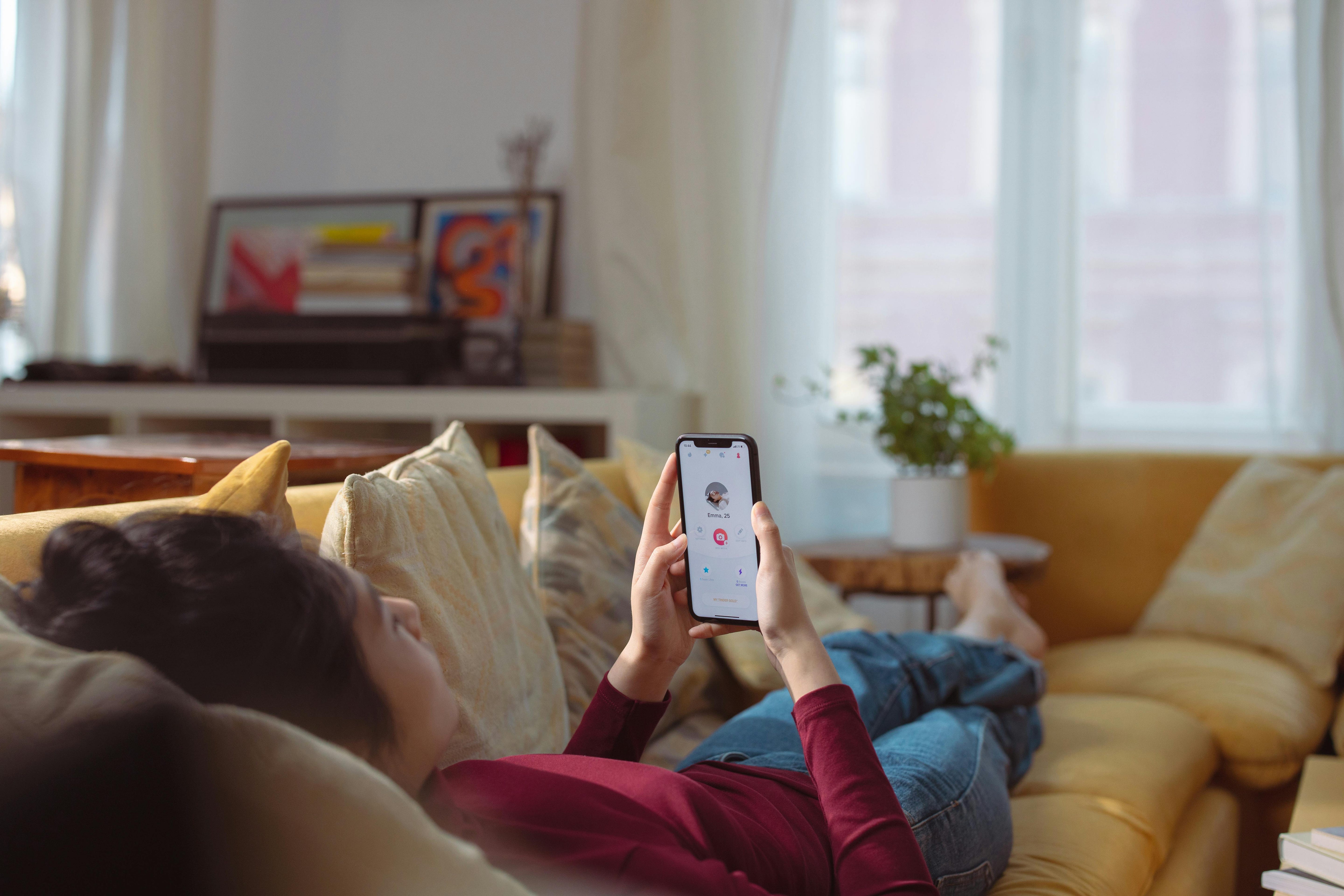 Woman laying on couch using dating app