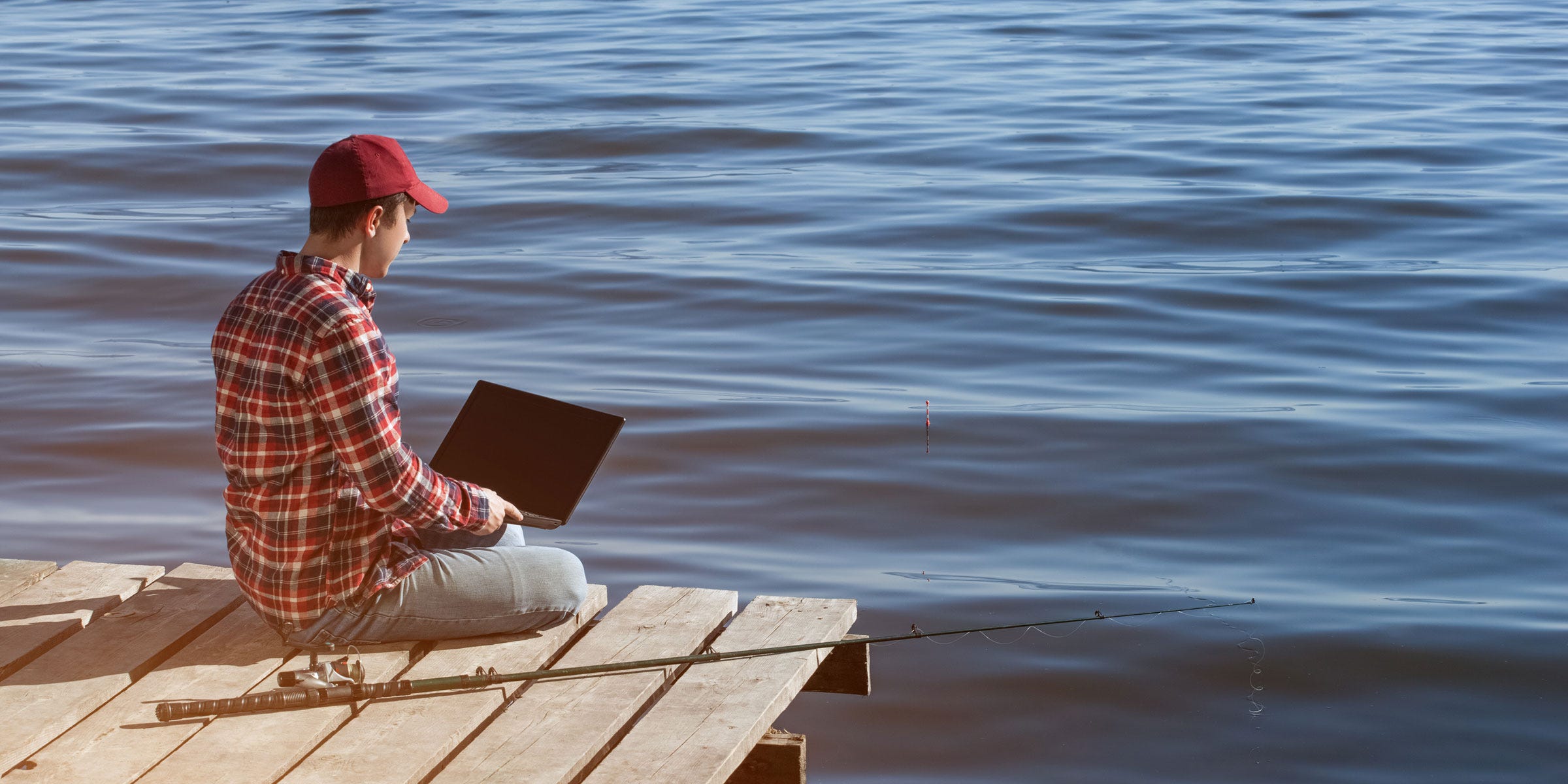 Man on dock with laptop gone writing instead of fishing.