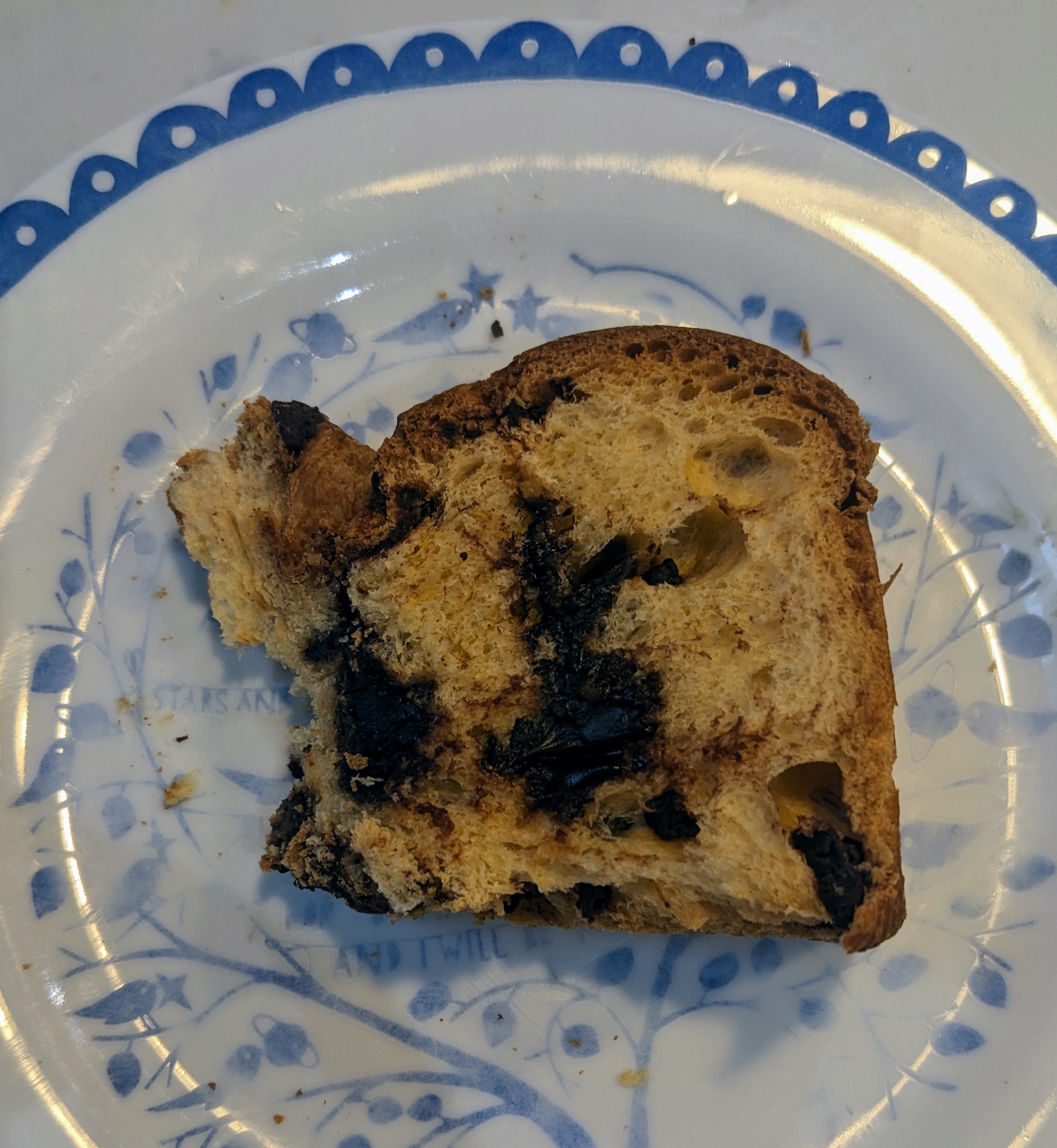 A slice of chocolate panettone sits on a blue and white patterned plate