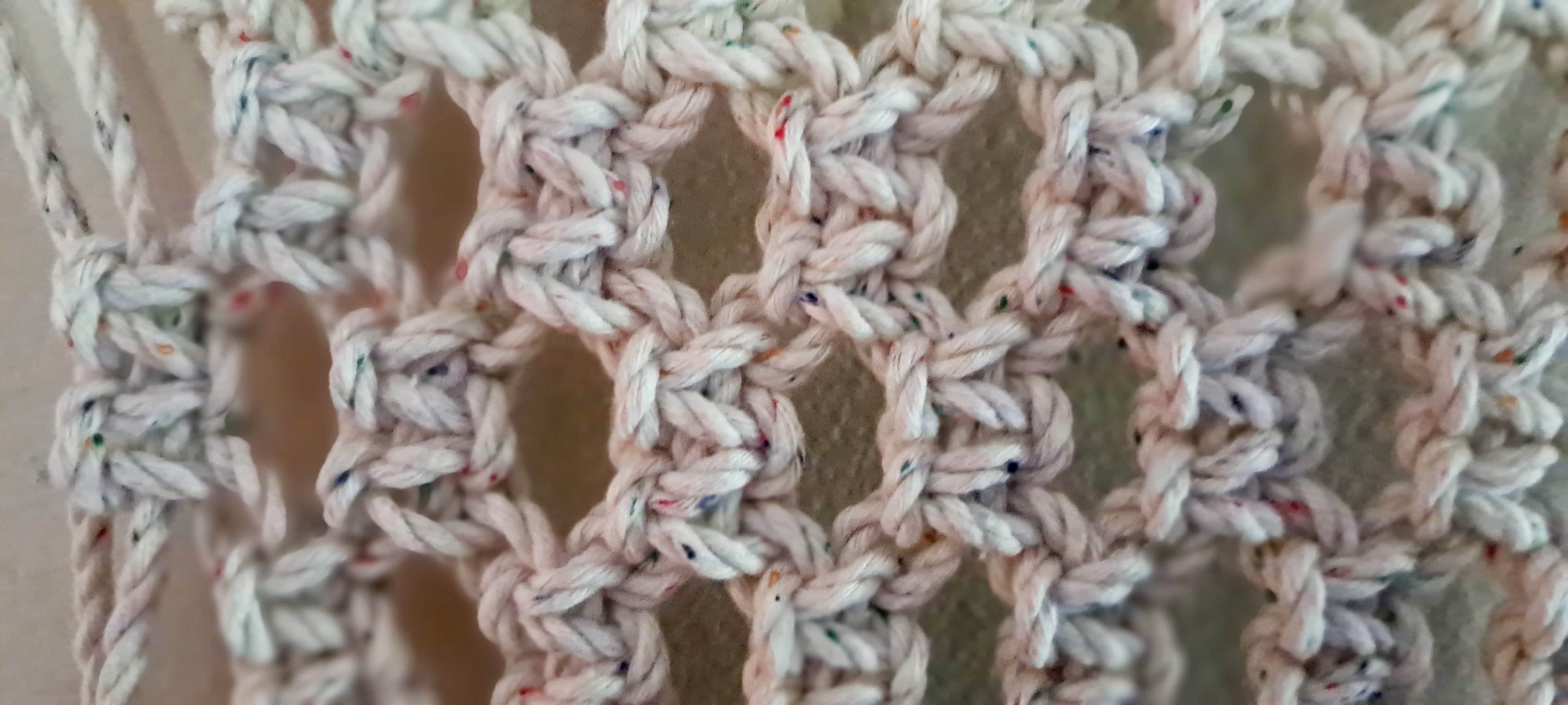 close up image of macrame knots in white cord which is speckled with multi-coloured neps