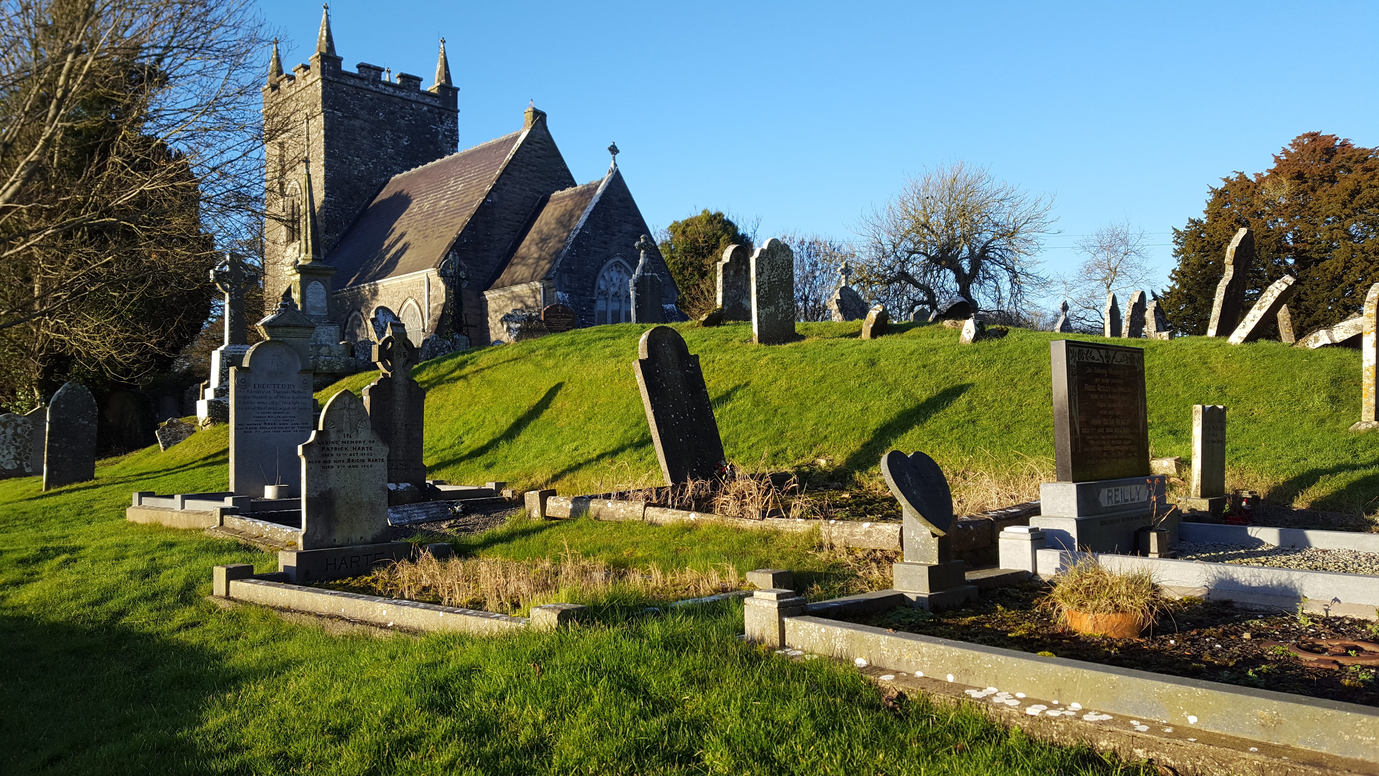 The graveyard at the church of St Patrick, with headstones leaning at crazy angles, clearly shows that the church is located upon a raised area, possibly from a previous structure.