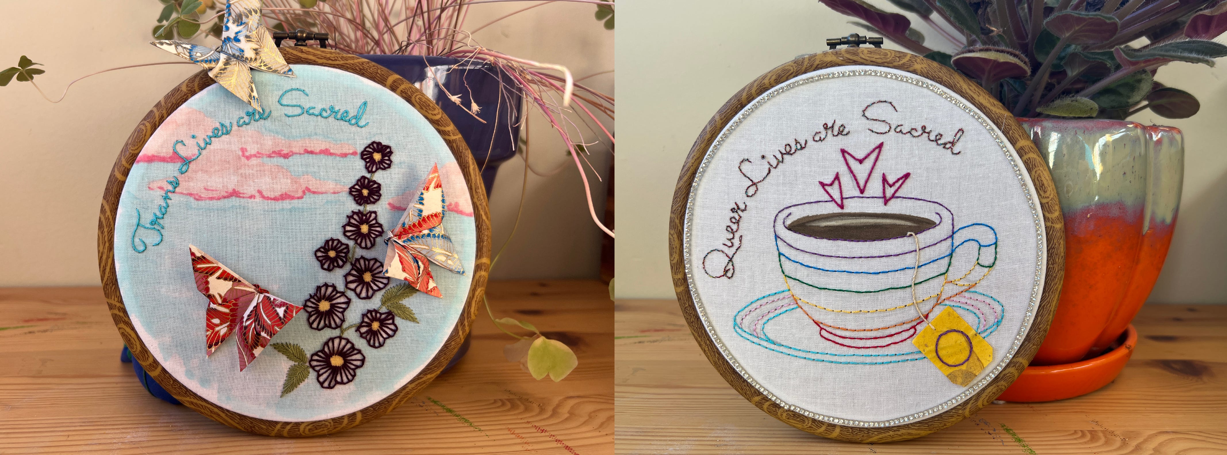 Two side-by-side photos of mixed-media embroidery pieces in round hoops. The image on the left shows a blue sky with pink clouds in marker with stitched flowers and origami butterflies. The text on this piece reads: "Trans Lives are Sacred." The piece on the right is of a teacup on a saucer with embroidered hearts rising from it like steam might. The cup is outlined in rainbow embroidery stripes and the saucer is outlined in trans pride colours. There is a tea tag hanging over the edge of the cup, which is made to look like the intersex pride flag. The text on this piece reads: "Queer Lives are Sacred." 