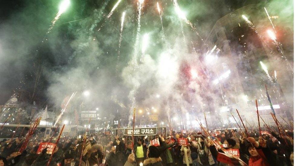 Protesters set off fireworks during a candle light vigil calling for impeached President Park Geun-hye to step down, near the presidential house in Seoul, South Korea, on 31 December