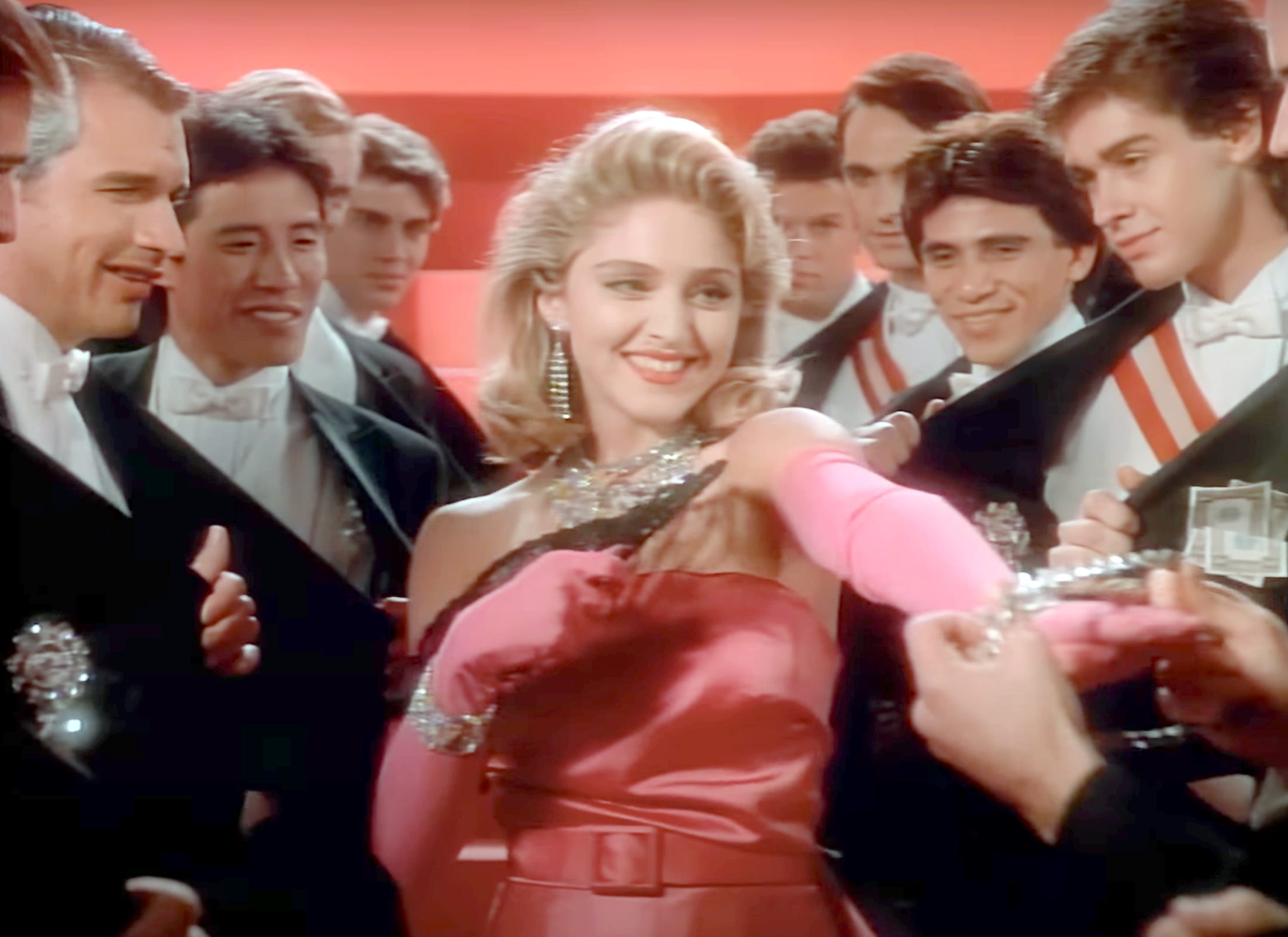 Madonna in the video for material girl, receiving jewels from the extras
